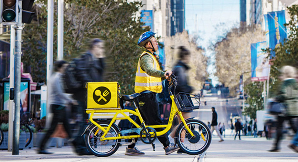 Food delivery service on yellow bike on Bourke street